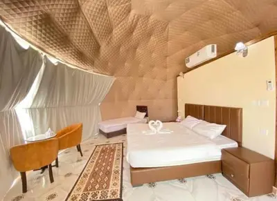 a bedroom with a bed and a table and a chair at Miral Night Camp in Wadi Rum