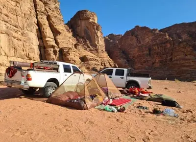 a tent and a truck parked in the desert at Miral Night Camp in Wadi Rum