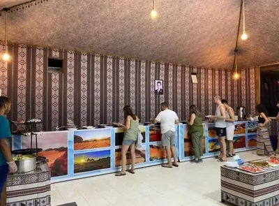 a group of people standing around a counter in a restaurant at Miral Night Camp in Wadi Rum
