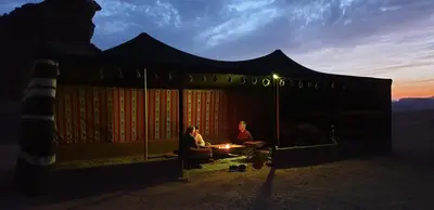 two people sitting in a tent at sunset at Real Bedouin Experience Tours & Camp in Wadi Rum