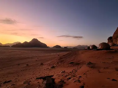 a sunset in the desert with mountains in the background at Wadi Rum Bubble Camp in Wadi Rum