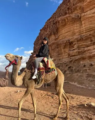 a woman riding on a camel in the desert at Wadi Rum Bubble Camp in Wadi Rum