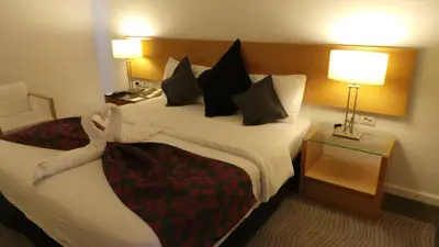 a hotel room with a large bed and a night stand at Amman Airport Hotel in Al Qasţal