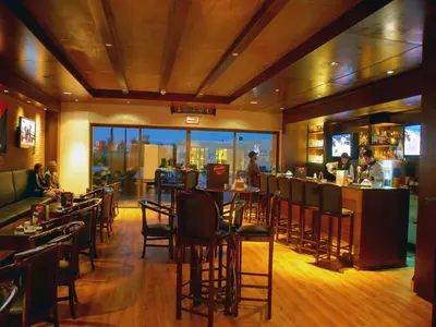 a restaurant with tables and chairs and a bar at Amman Airport Hotel in Al Qasţal