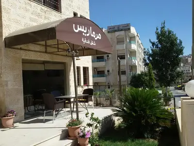 a table with an umbrella in front of a building at Marmaris Hotel Apartments in Amman