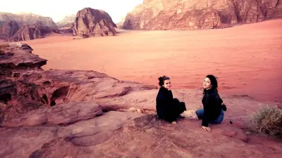 two women sitting on a rock in the desert at Bedouin Village Hostel in Wadi Rum