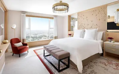 a bedroom with a large white bed and a red chair at Four Seasons Hotel Amman in Amman