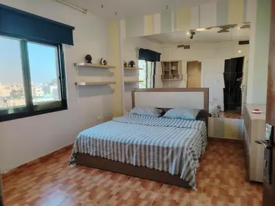 a bedroom with a bed and a large window at Abu alzoz home سكن مشترك in Amman