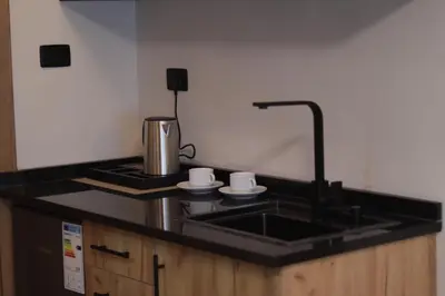 a kitchen sink with two cups and a coffee maker at Al Jawhara Hotel Suites in Amman