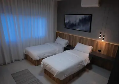 a hotel room with two beds and a tv at Al Jawhara Hotel Suites in Amman
