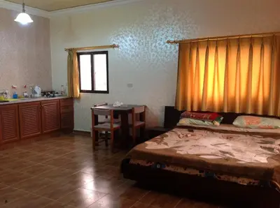 a bedroom with a bed and a table and a kitchen at Murshed Motel in Ash Shūnah ash Shamālīyah