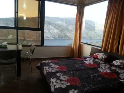 a bedroom with a bed and a table and windows at Murshed Motel in Ash Shūnah ash Shamālīyah