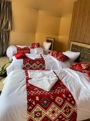 two beds with red and white blankets and pillows at Bronze Mountains Camp Wadi Rum in Aqaba