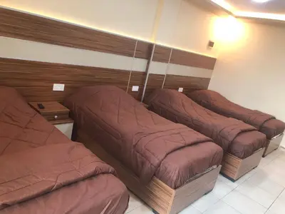 three beds are lined up in a room at Al Deyafa Hotel in Aqaba