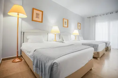 two beds in a hotel room with two lamps at Grand Hotel Madaba in Madaba