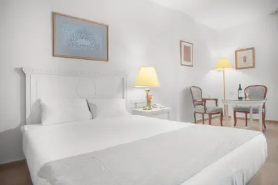 a white bedroom with a large bed and a table at Grand Hotel Madaba in Madaba