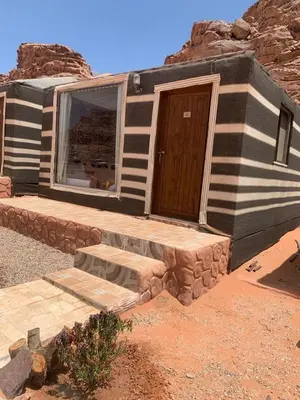 a house in the desert with a wooden door at WADI RUM-Bedouin Tents and Jeep Tours in Wadi Rum