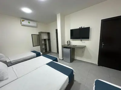 a hotel room with two beds and a television at Relax House For Studio Rooms Apartments ريلاكس هاوس للشقق المفروشة in Aqaba