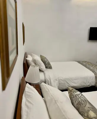 two beds in a hotel room with a lamp at Bonita Inn in Amman