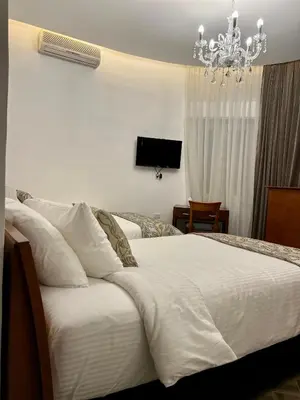 a bedroom with a large white bed with a chandelier at Bonita Inn in Amman