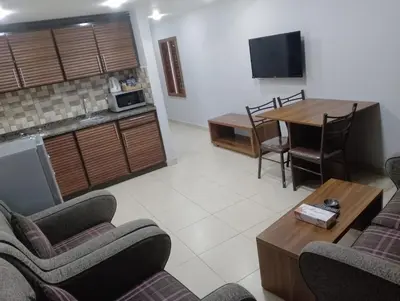 a living room with two couches and a table and a kitchen at Shami Plaza Hotel in Amman