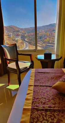 a bedroom with a bed and chairs and a large window at Shaqilath Hotel in Wadi Musa