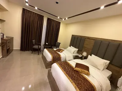 a hotel room with two beds and a desk at Shaqilath Hotel in Wadi Musa