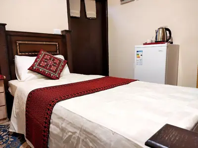 a bed with a red and white blanket and a refrigerator at Majido Hotel in Wadi Musa