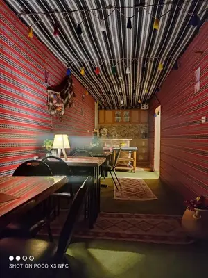 a room with a red wall with a table and chairs at Majido Hotel in Wadi Musa