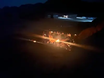 a group of people standing around a fire at night at Bedouin host camp& with tour in Wadi Rum