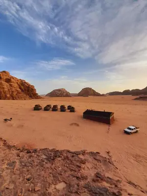 a desert with a car parked in the desert at Bedouin host camp& with tour in Wadi Rum
