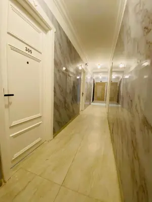 an empty hallway with a white door and marble walls at Arabesque Hotel in Amman