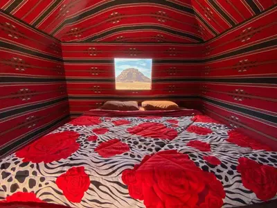 a red room with a bed with red roses on it at Wadi Rum Magic Nature Camp in Wadi Rum