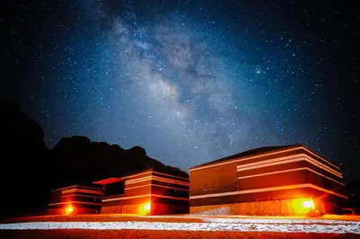 a starry night with the milky way behind two buildings at Wadi Rum Magic Nature Camp in Wadi Rum