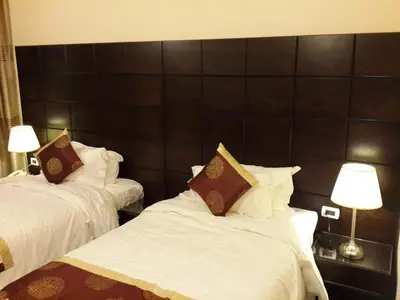 two beds in a room with white sheets and pillows at Al Thuraya Hotel in Amman