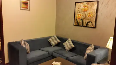 a living room with a blue couch and a painting at Al Thuraya Hotel in Amman
