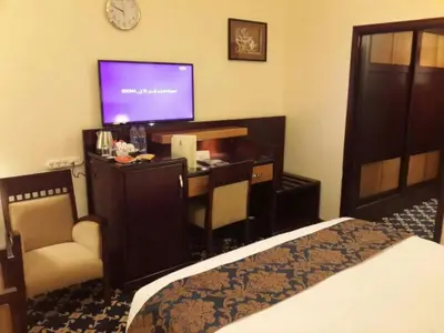 a hotel room with a bed and a desk with a television at Al Thuraya Hotel in Amman