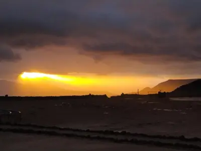 a sunset with the sun setting in the distance at Mujib Castle Gate Camp in Dhībān