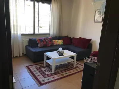 a living room with a blue couch and a white table at Behind Mecca Mall in Amman