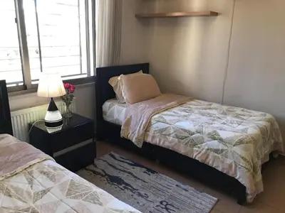 a bedroom with two beds and a table with a lamp at Behind Mecca Mall in Amman