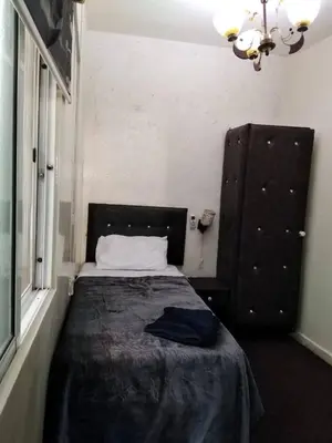 a small bedroom with a bed with a black blanket at Al Midan Hotel in Amman