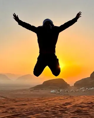 a man jumping in the air in the desert at RUM SOlARIS BEDOUIN CAMP in Wadi Rum