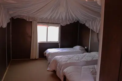 a bedroom with three beds and a window at Magic Wadi Rum in Wadi Rum