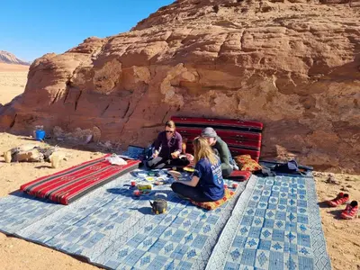 a group of people sitting on a blanket on the beach at Magic Wadi Rum in Wadi Rum