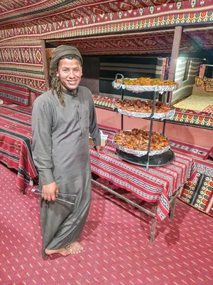 a man standing in front of a table with food at Star City Camp wadirum in Wadi Rum