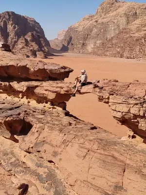 a man sitting on a rock in the desert at Star City Camp wadirum in Wadi Rum