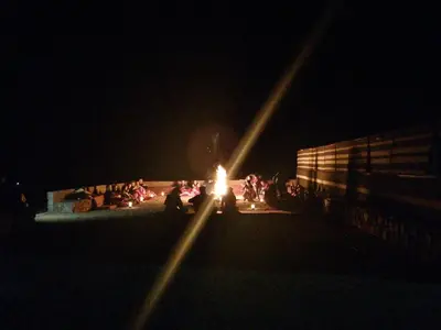 a group of people sitting around a train at night at Wadi Rum Excursions in Wadi Rum