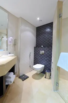 a bathroom with a toilet and a sink and a shower at Corp Amman Hotel in Amman