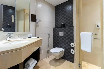 a bathroom with a toilet and a sink and a mirror at Corp Amman Hotel in Amman