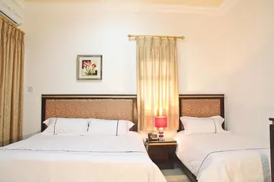 a bedroom with two beds and a table with a lamp at Golden Rose Hotel in Aqaba